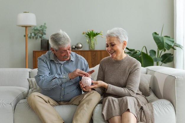 Saving money investment for future senior adult mature couple holding piggy bank putting money coin