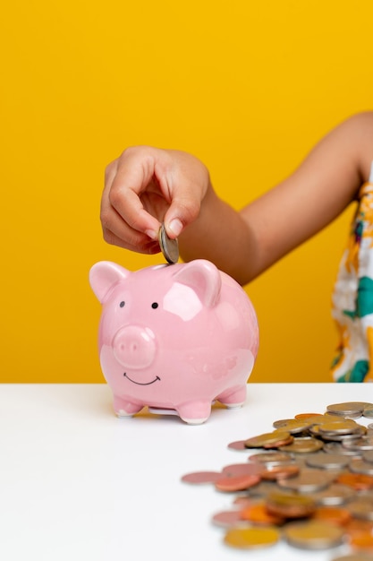 Saving money Young girl's hand balances coins in a piggy bank pink pig planting a savings plan for children money saving concept