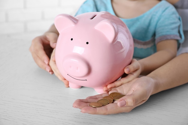 Savings concept Hands holding piggy bank and pile of coins close up