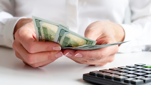 Savings finances economy and home concept close up of woman with calculator counting money and making notes at home