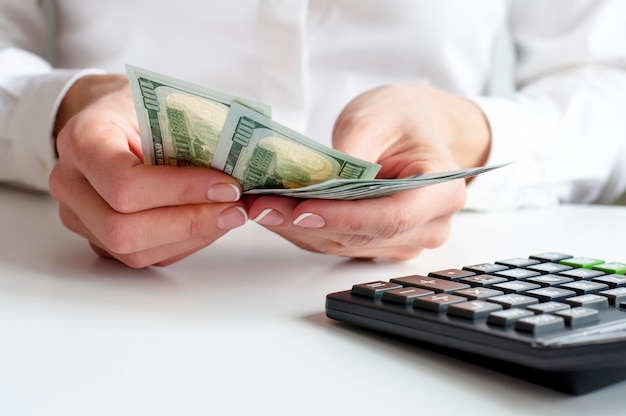 Savings finances economy and home concept close up of woman with calculator counting money and making notes at home