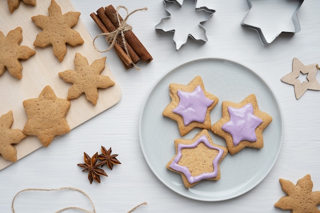 Savory gingerbread cookies with violet icing served on gray plate on wooden table with cutters