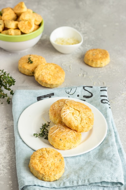 Savory scones or cookies with cheese and thyme on a white ceramic plate.