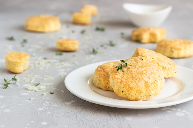 Savory scones or cookies with cheese and thyme on a white ceramic plate.