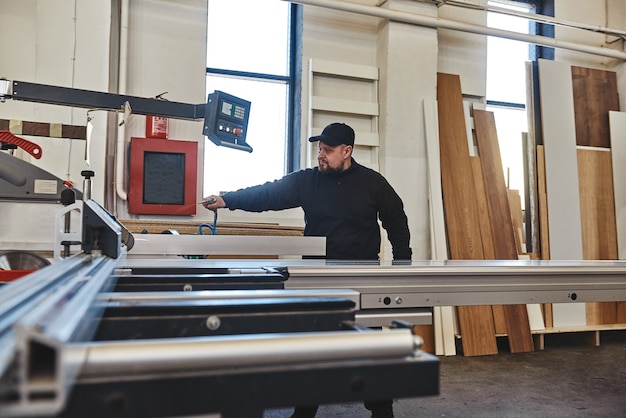 Sawing up of a wooden board on a sliding table saw woodworking and carpentry production