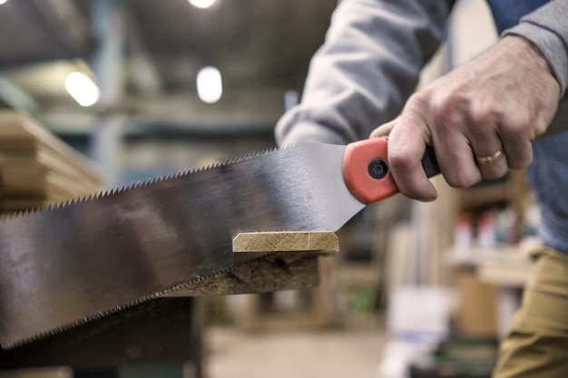 Photo sawing a wooden board with special japanese hand saw or hacksaw during carpentry