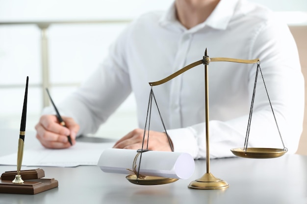 Scales of justice with sealed scroll and blurred view of notary on background