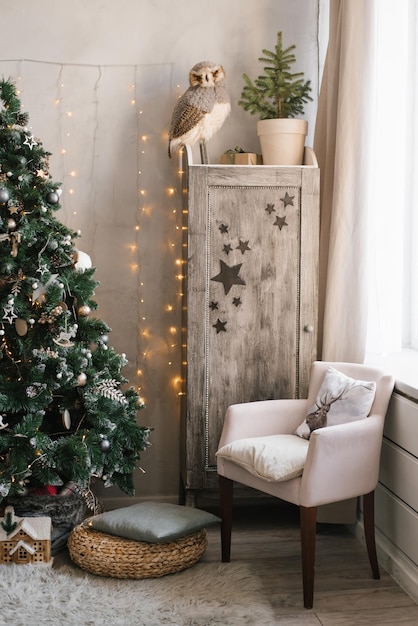 Scandinavian Christmas interior decorated with a Christmas tree in the children's room Wardrobe with children's toys armchair