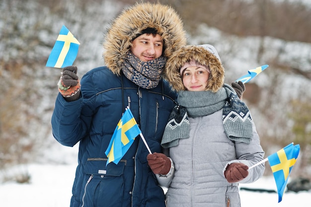 Scandinavian couple with Sweden flag in winter swedish landscape