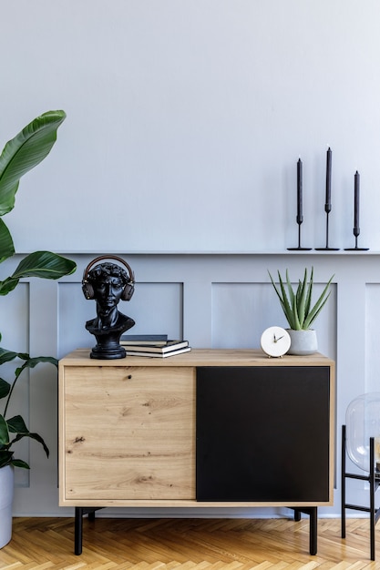 Scandinavian home interior of living room with design wooden commode, tropical plant, lamp, decoration, candle, copy space and elegant accessories in stylish home decor.