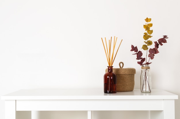 Scandinavian hygge style, home interior  aroma diffuser with wooden sticks, straw basket, dried eucalyptus branches