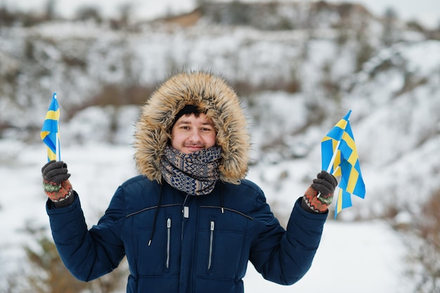 Scandinavian man with Sweden flag in winter swedish landscape