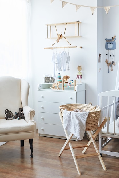 Scandinavian style white interior children's room, bedroom, nursery. Baby cot with Ã¢ÂÂcanopy. Wooden shelves and toys. Wicker cradle with legs