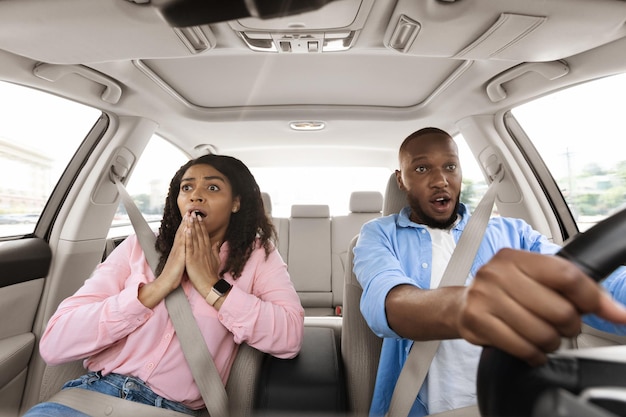 Scared black couple driving car windshield view