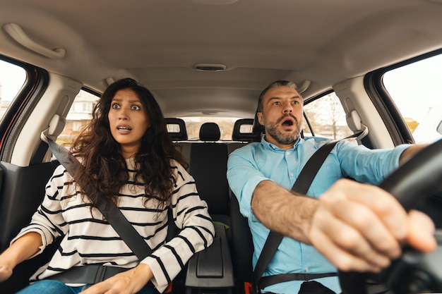 Scared couple driving car front portrait windshield view