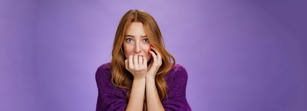 Scared insecure woman with red hair biting fingernails feeling frightened as home alone hearing weir