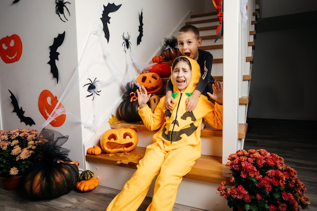 Scared kids in costumes at home decorated for halloween