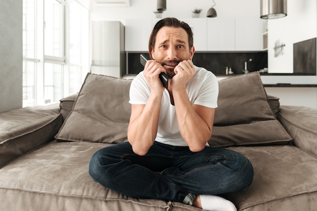 Scared mature man sitting on a sofa