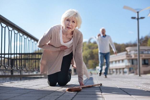 Scared puzzled old woman resting and feeling heart attack while aged man running to help her