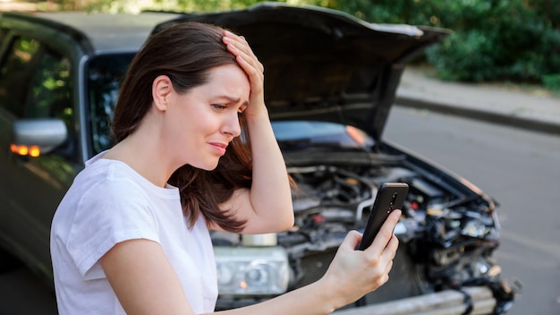 Scared woman in stress holding her head after auto crash calling to auto insurance for help Driver woman in front of wrecked car in car accident Dangerous road traffic situation