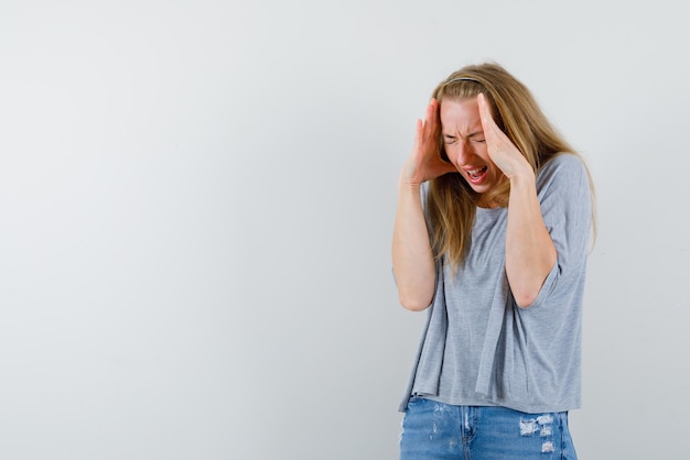 The scared young woman is putting her hands on temples on white background