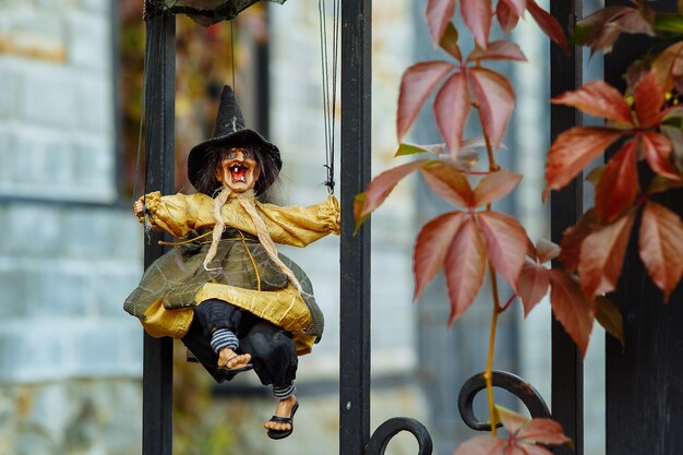 a scary witch doll on a wroughtiron lattice among autumn plants