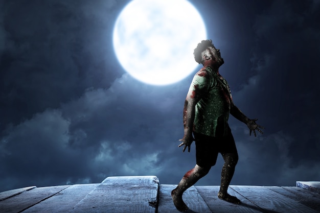 Scary zombie with blood and wound on his body standing with a night scene background