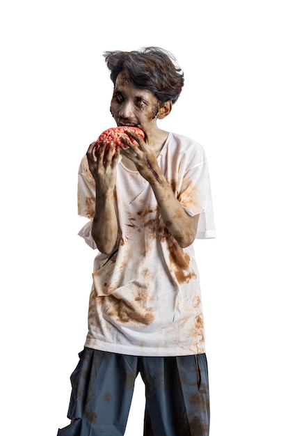 A scary zombie with blood and wounds on his body walking while eating a human brain isolated over a white background