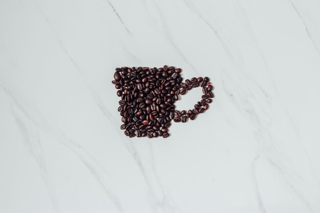 Photo scattered coffee beans and coffee espresso cup on marble backdrop