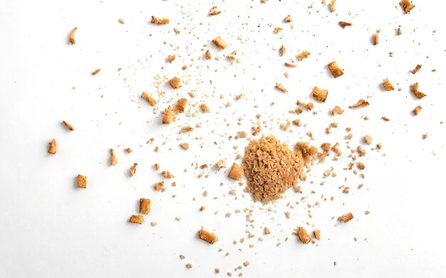 Photo scattered crumbs of roasted white bread on a white background closeup