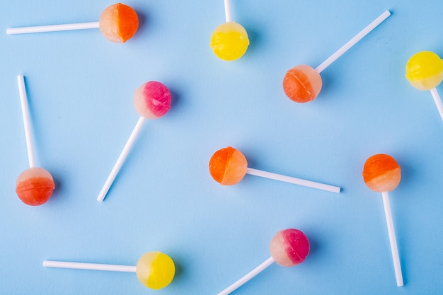 Scattered lollipop candies on blue background top view