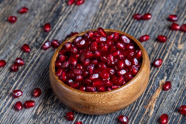 Scattered pomegranate seeds on a wooden board red ripe pomegranate seeds are scattered on a wooden cutting board