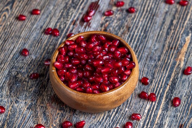 Scattered pomegranate seeds on a wooden board red ripe pomegranate seeds are scattered on a wooden cutting board