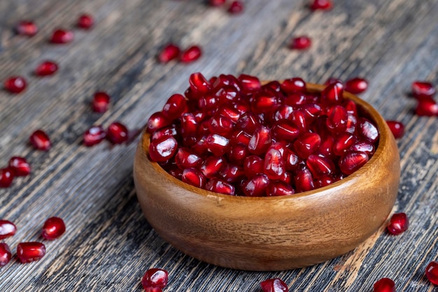 Scattered pomegranate seeds on a wooden board red ripe pomegranate seeds are scattered on a wooden cutting board