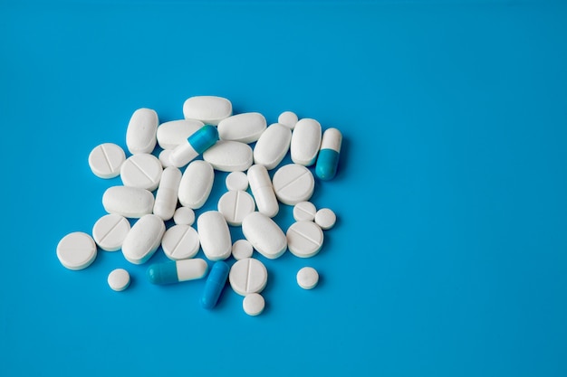 Scattered white pills on blue table