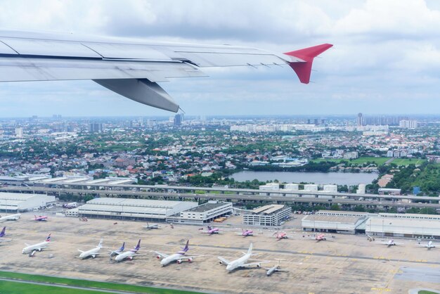 Scenery from airplane 's window after taking off ,  seeing wing of airplane and landscape of Bangkok and Don Muang airport