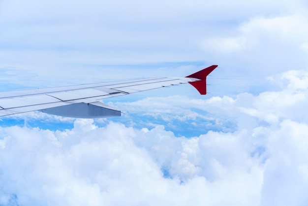 Scenery from airplane 's window seeing wing of airplane white clouds and blue sky