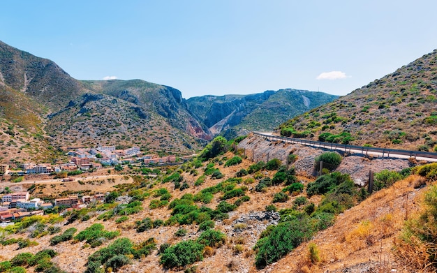 Scenery and highway in Carbonia near Cagliari in Sardinia in Italy. View with nature in the road. Mountains and hills on the background.