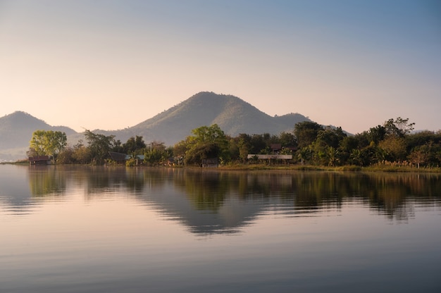 Scenery of mountain with traditional village floating on Lam Taphoen reservoir in the morning at Suphanburi