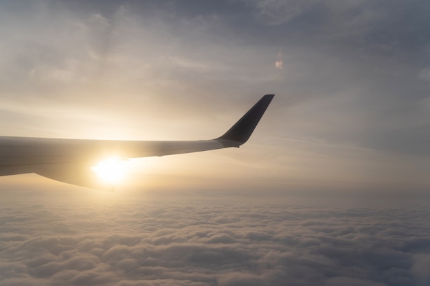 The scenery view above the cloud and airplane wing with sunset. View though window on the airplane.