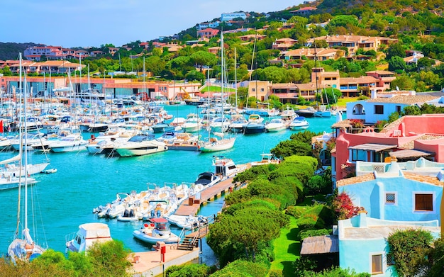 Scenery with Marina and luxury yachts at Mediterranean Sea of Porto Cervo in Sardinia Island of Italy in summer. Landscape View on Sardinian town port with ships and boats in Sardegna. Mixed media.