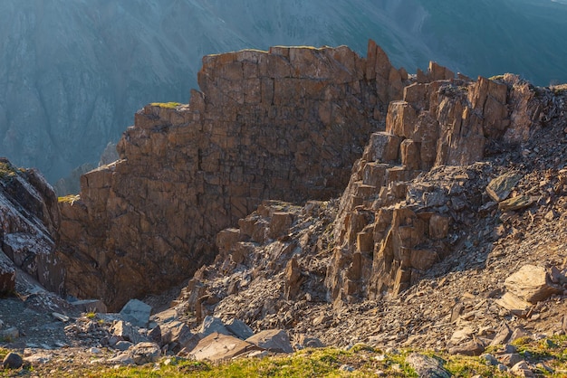 Scenic alpine landscape with mountain wall and sharp stones in sunlight Awesome mountain view from cliff at very high altitude Beautiful mountain scenery on abyss edge with sharp rocks and couloirs