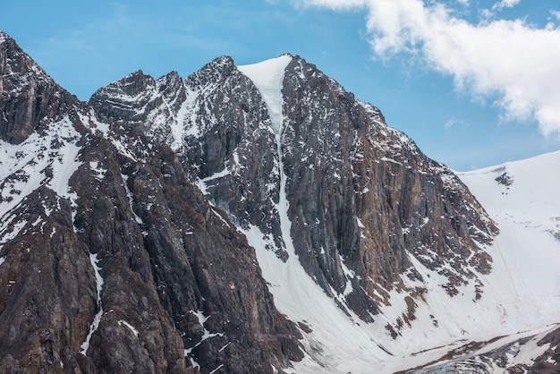 Scenic alpine landscape with snowy mountain peak in sunny day Awesome landscape with rocky pinnacle with snow in sunlight Beautiful view to snow mountain top and sharp rocks at very high altitude