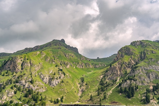 Scenic Alps with green hill under overcast sky