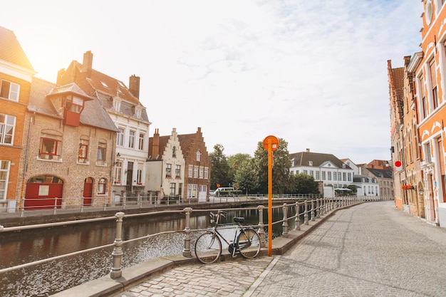 Scenic city view of Bruges canal with beautiful medieval colored houses and old bike in the morning hour at sunrise Belgium