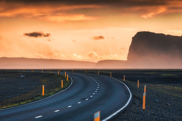 Scenic curved highway asphalt road with golden sky and mountain in the sunset