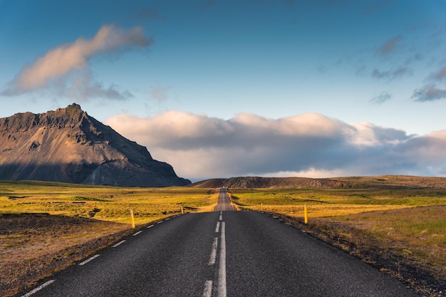 Scenic empty asphalt straight road with sunlight and mountain view at Iceland