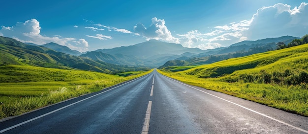 Scenic Open Road Leading Through Lush Green Countryside Towards Majestic Mountains Under a Clear Blue Sky