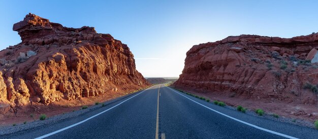 Scenic road in the dry desert with red rocky mountains in background