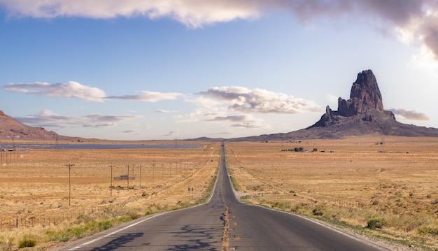 Scenic road in the dry desert with red rocky mountains in background